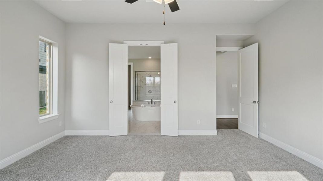 Unfurnished bedroom with multiple windows, light colored carpet, a ceiling fan, and connected bathroom Unfurnished bedroom with multiple windows, light colored carpet, a ceiling fan, and connected bathroom