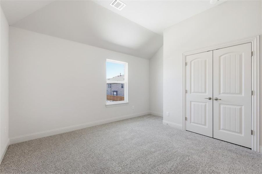 Unfurnished bedroom with light carpet, vaulted ceiling, and a closet