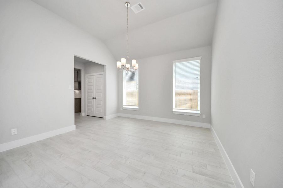 An inviting dining space seamlessly woven into the open concept, connecting the family room and kitchen. Revel in the stunning floors, soothing paint palette, and the crowning touch of a sleek chandelier – a perfect setting for shared meals and cherished moments. Sample photo of completed home with similar floor plan. Actual colors and selections may vary.