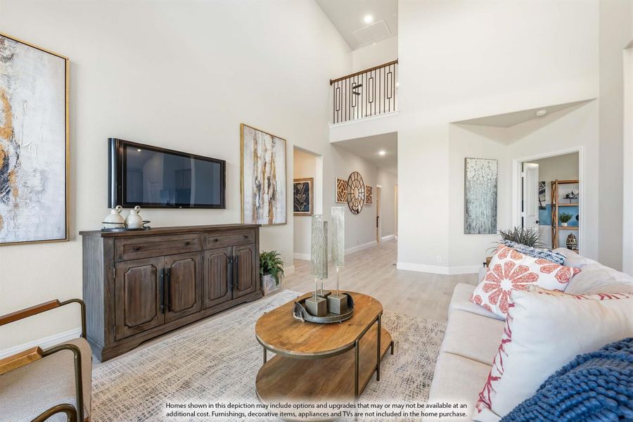 Living room with vaulted ceiling, wood floors, wall-mounted TV, and open staircase overlook above.