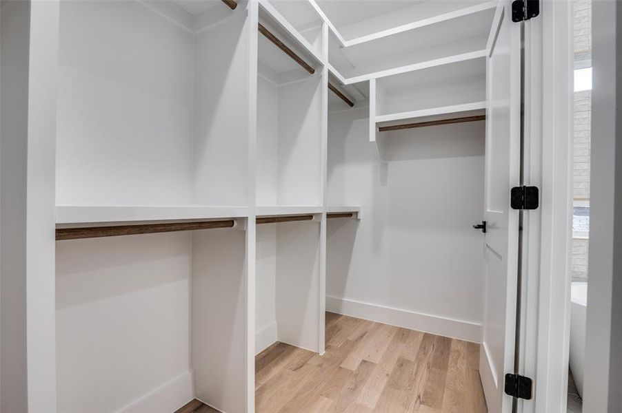 Walk in closet with light wood-style flooring