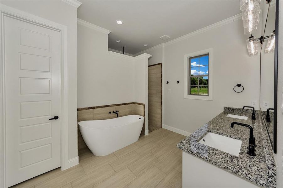 Full bath with double vanity, a freestanding tub, crown molding, a shower, and recessed lighting
