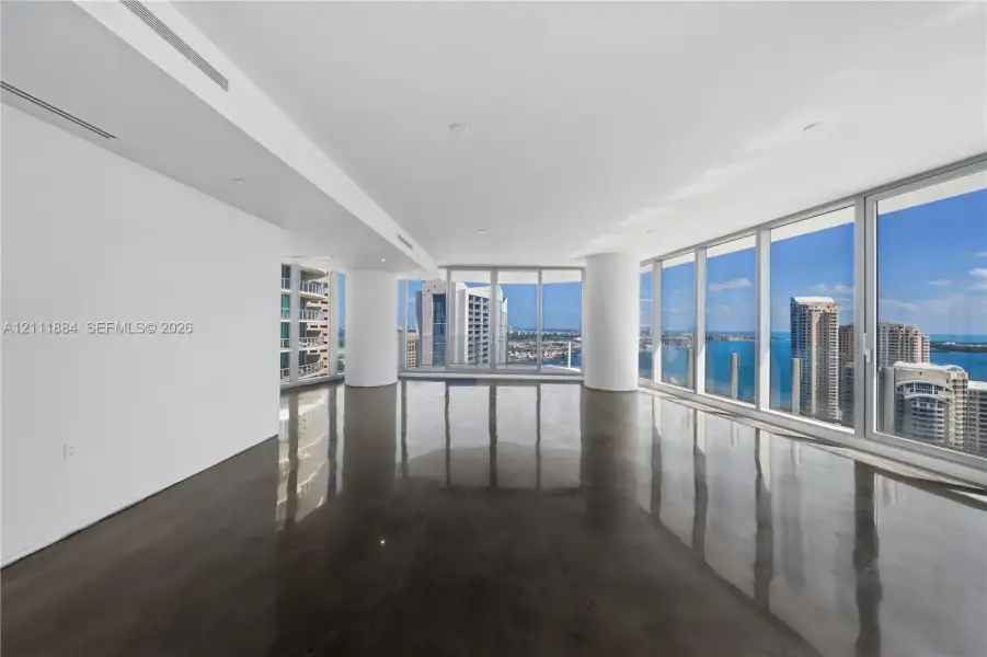 Expansive open-concept interior featuring polished concrete flooring, floor-to-ceiling glass windows, and panoramic water and urban skylines Expansive open-concept interior featuring polished concrete flooring, floor-to-ceiling glass windows, and panoramic water and urban skylines