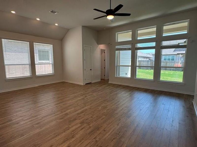 A well-lit living space with wood-look flooring and ample natural illumination from multiple windows.