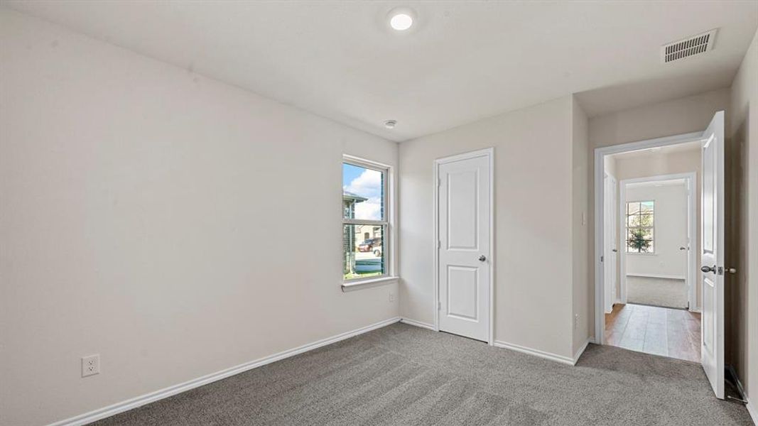 Unfurnished bedroom featuring dark carpet, multiple windows, and a closet