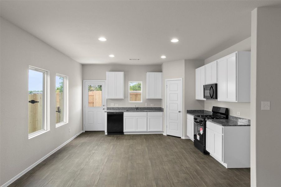 Kitchen featuring black appliances, dark wood-type flooring, healthy amount of natural light, recessed lighting, and white cabinets Kitchen featuring black appliances, dark wood-type flooring, healthy amount of natural light, recessed lighting, and white cabinets