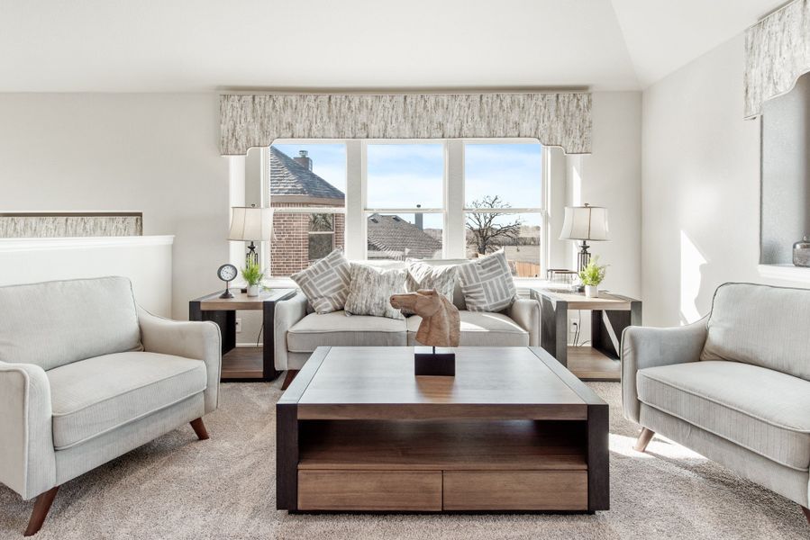 Living room with neutral sofa, two armchairs, wood coffee table, and large windows with patterned valances