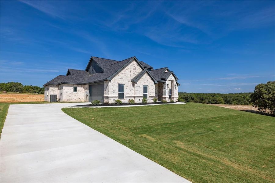 French country home with a garage, a front lawn, and central AC