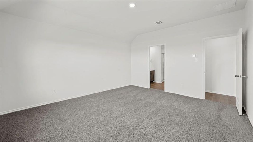 Spacious interior room featuring light-toned walls, grey carpet flooring, and a recessed ceiling light