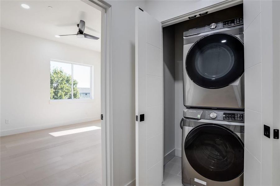 Laundry room featuring stacked washer / dryer, light wood-style floors, and a ceiling fan