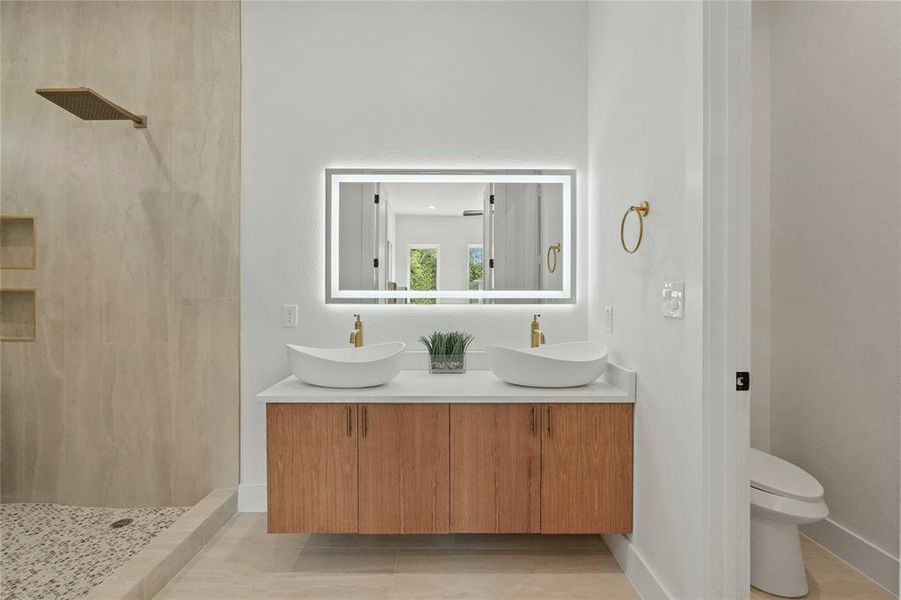 Bathroom with double vanity, a tile shower, and toilet