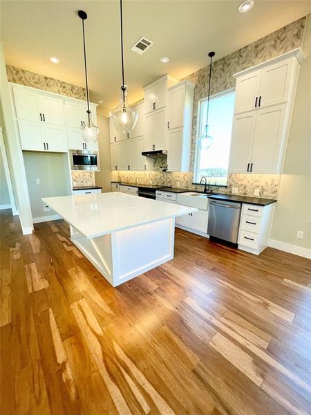 Kitchen with white cabinetry, a center island, and hanging light fixtures