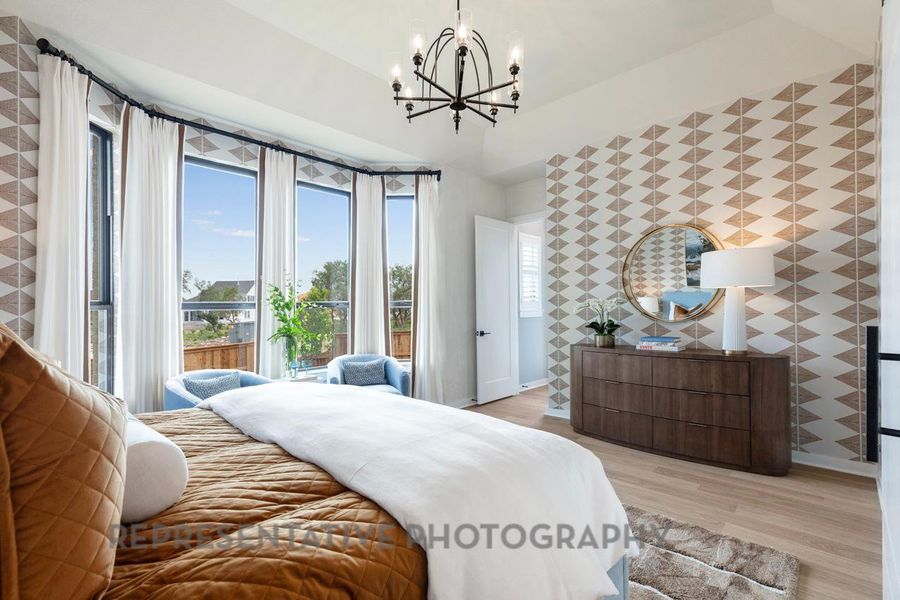 Bedroom featuring light wood-style flooring, a chandelier, and an accent wall Bedroom featuring light wood-style flooring, a chandelier, and an accent wall