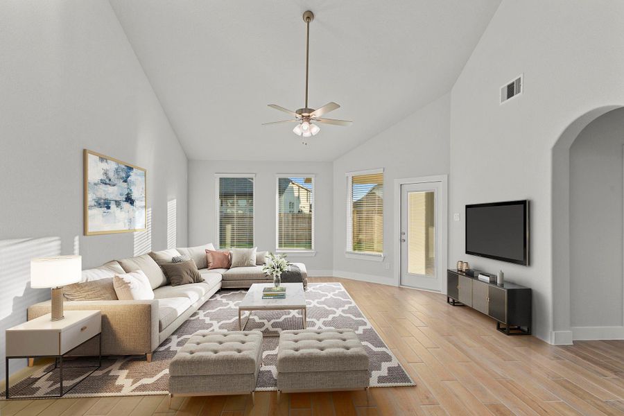 The spacious family room sits beyond the dining area and features a soaring ceiling and a wall of windows overlooking the backyard—creating a bright and welcoming retreat for everyday living. *Staged Photo* The spacious family room sits beyond the dining area and features a soaring ceiling and a wall of windows overlooking the backyard—creating a bright and welcoming retreat for everyday living. *Staged Photo*