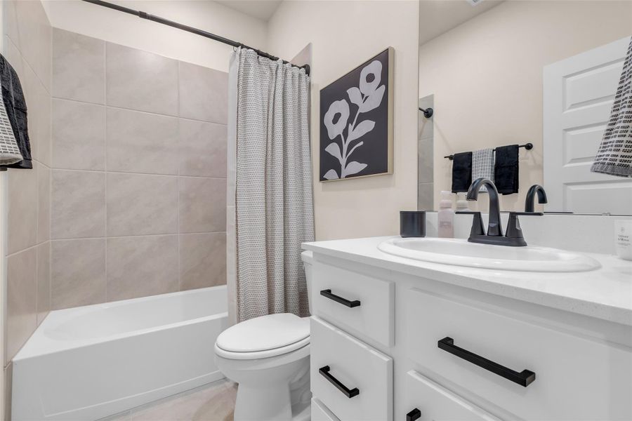 Secondary Bathroom-This bathroom features a modern design with a white vanity, sleek black fixtures, and a shower-tub combo with neutral tile. Secondary Bathroom-This bathroom features a modern design with a white vanity, sleek black fixtures, and a shower-tub combo with neutral tile.