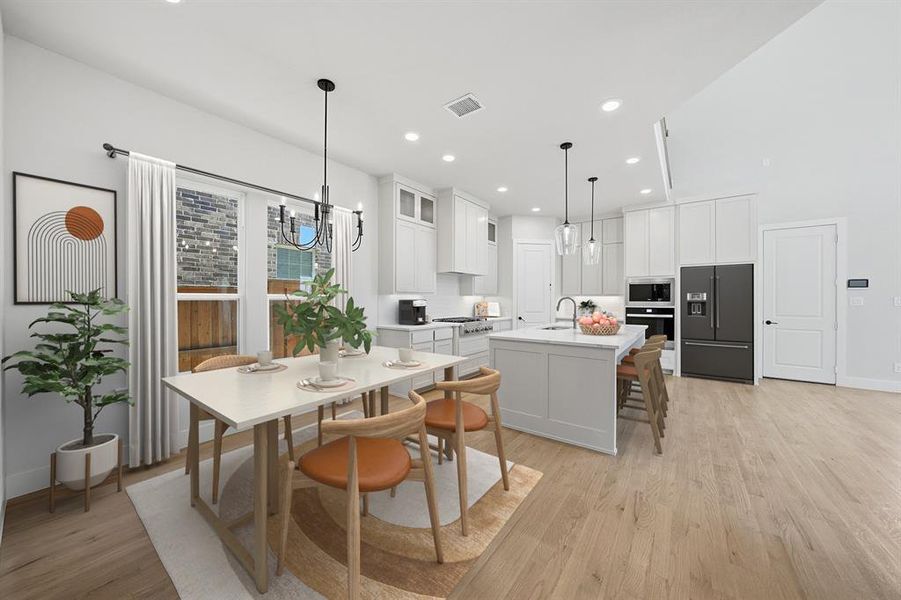 Kitchen with light wood finished floors, a breakfast bar, appliances with stainless steel finishes, white cabinets, and recessed lighting