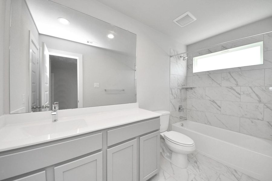 Secondary bath features tile flooring, bath/shower combo with tile surround, light stained wood cabinets, beautiful light countertop. Secondary bath features tile flooring, bath/shower combo with tile surround, light stained wood cabinets, beautiful light countertop.