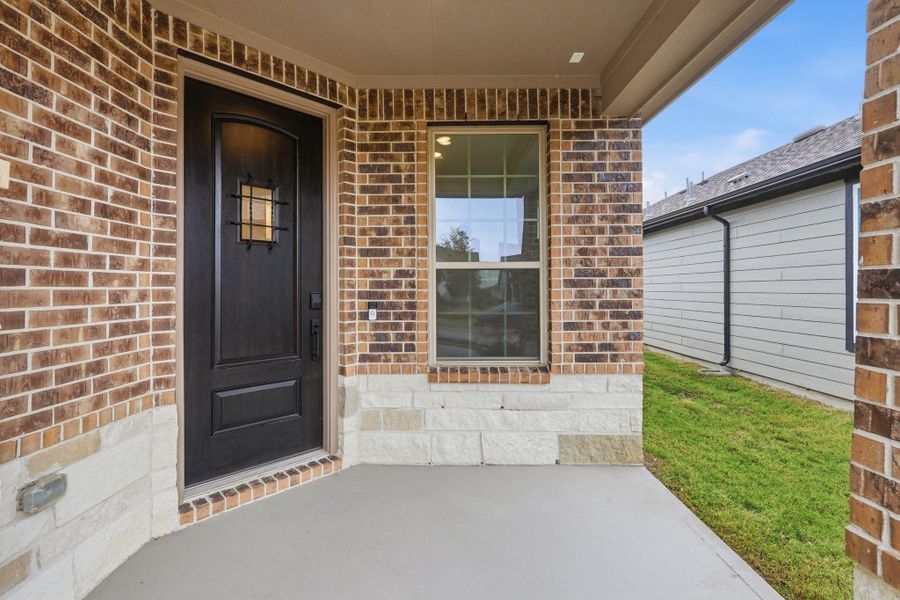 This covered porch provides a peaceful spot to pause, highlighted by a stylish dark front door and a large window that invites natural light.