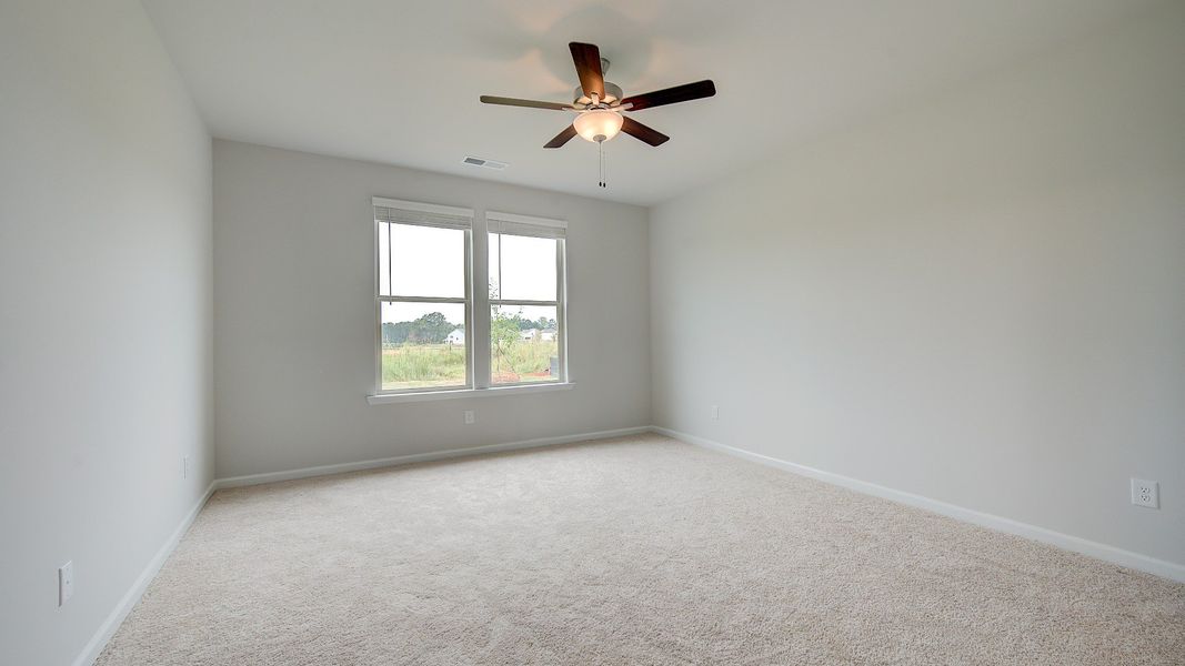 Spacious Meridian II primary suite with coffered ceiling, carpet flooring, and bay window at Brighton in Locust Grove, GA.