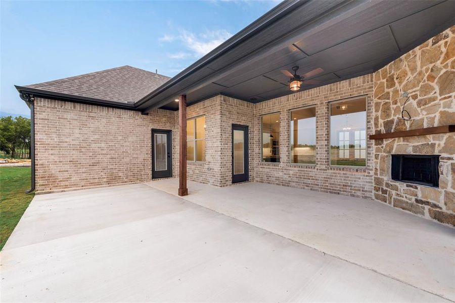 View of patio featuring ceiling fan and an outdoor stone fireplace View of patio featuring ceiling fan and an outdoor stone fireplace