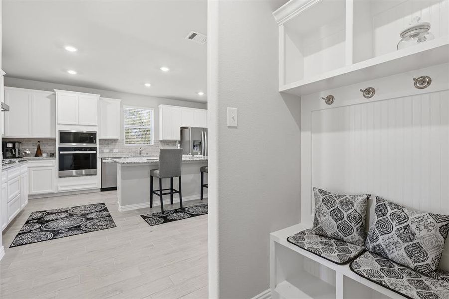 Built-in mudroom bench with coat hooks and overhead shelving