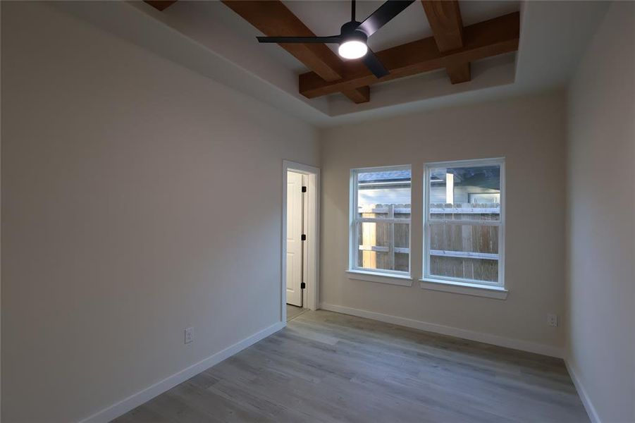 Empty room featuring coffered ceiling, ceiling fan, beamed ceiling, and wood finished floors