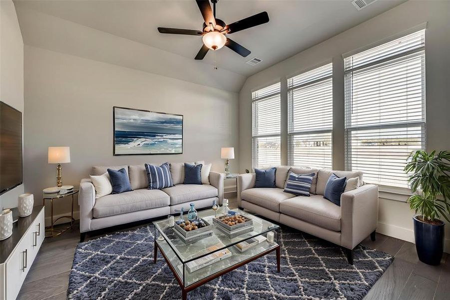 Living room featuring dark wood finished floors, a ceiling fan, vaulted ceiling, visible vents, and baseboards