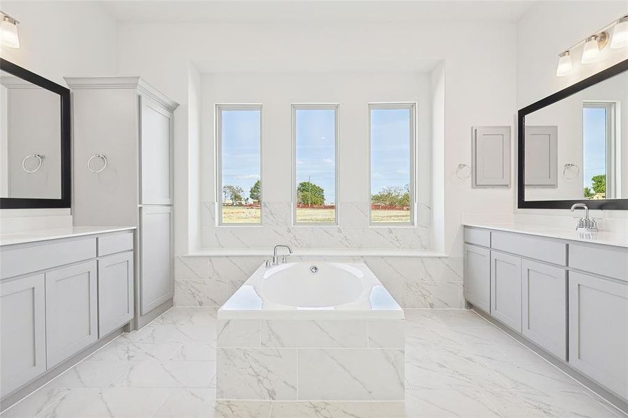 Bathroom featuring vanity, a relaxing tiled tub, and plenty of natural light