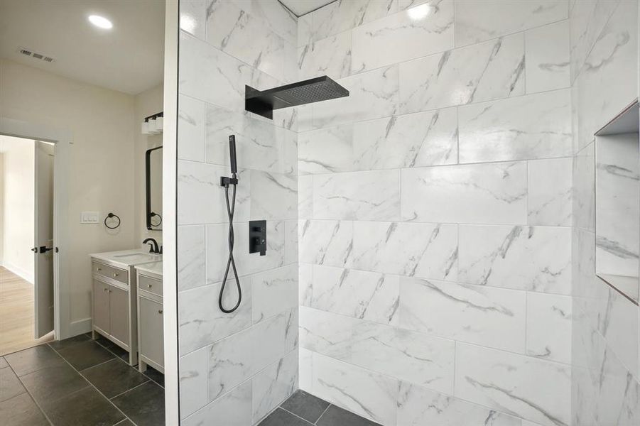 Bathroom featuring a tile shower and vanity