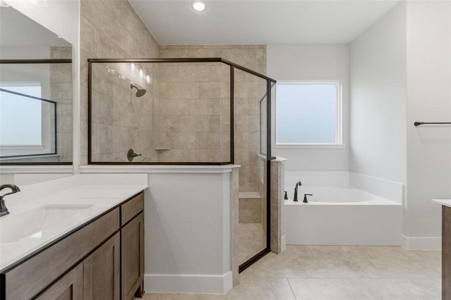 Bathroom featuring a corner soaking tub with matte black fixtures, a glass-enclosed shower with tile surround, a built-in shower bench, and a vanity with a white countertop and integrated sink
