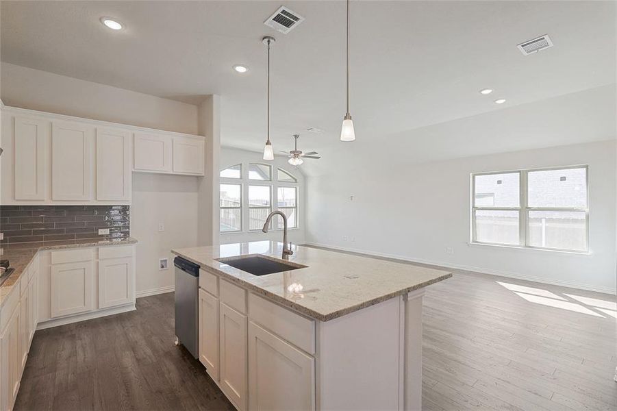 Kitchen with stainless steel dishwasher, light stone countertops, sink, and plenty of natural light