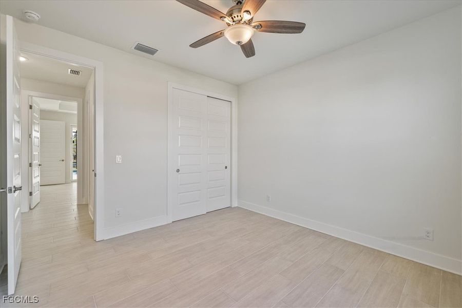 Unfurnished bedroom with wood tiled floors, ceiling fan, and a closet