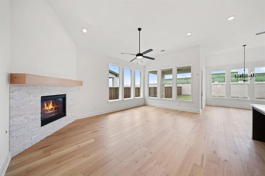 Unfurnished living room with plenty of natural light, light wood-style floors, a fireplace, and recessed lighting Unfurnished living room with plenty of natural light, light wood-style floors, a fireplace, and recessed lighting