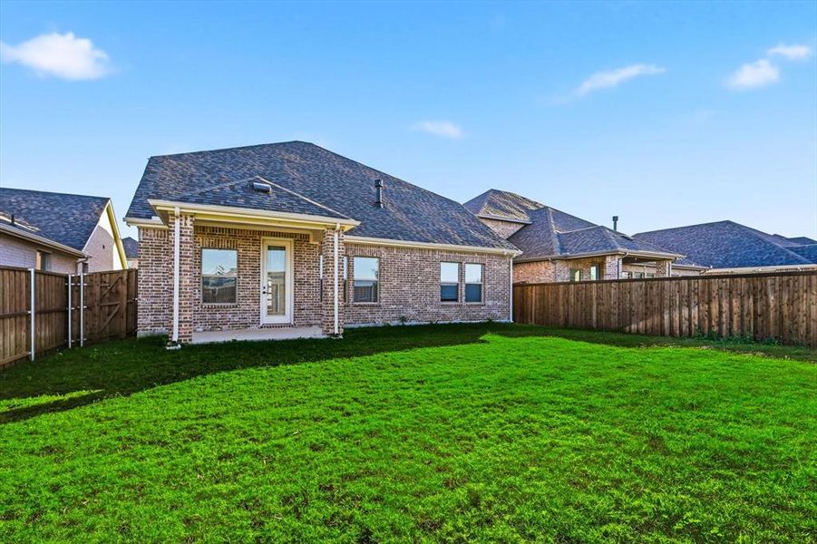 Rear view of house with a patio, brick siding, a fenced backyard, and a shingled roof