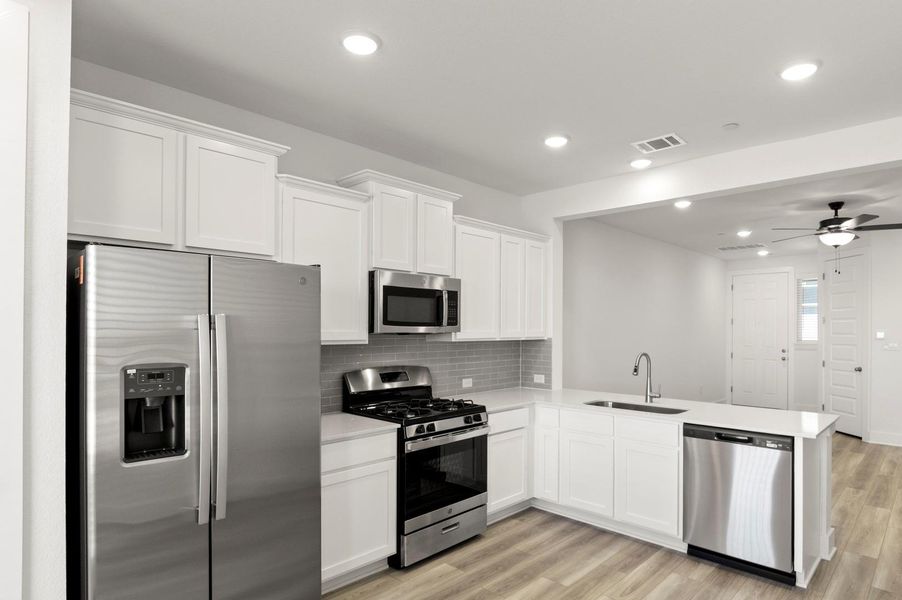Kitchen featuring stainless steel appliances, white cabinetry, light wood-type flooring, recessed lighting, and decorative backsplash
