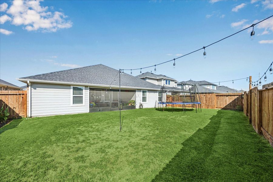 View of the back of the home, gutters, screened patio, landscpaing lights!  This home has it all!