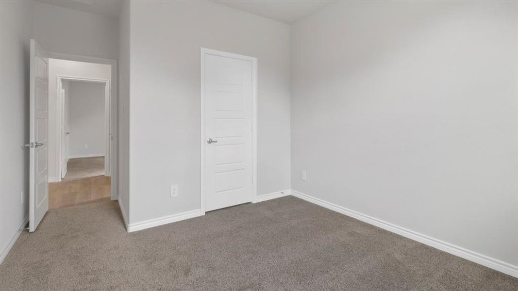 Unfurnished bedroom featuring dark colored carpet and baseboards
