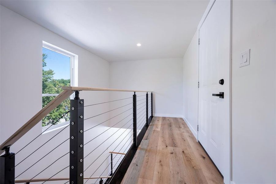 Hallway featuring plenty of natural light and light hardwood / wood-style floors entry to rooftop patio