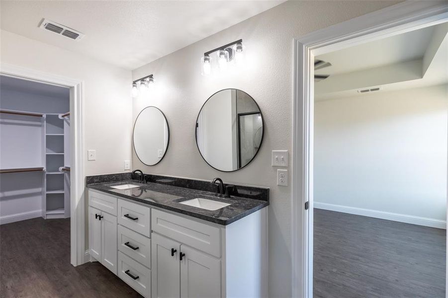 Dual vanity with dark stone countertop and undermount sinks, round mirrors, and black hardware