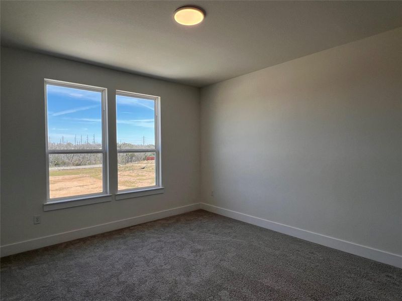 Carpeted spare room featuring baseboards