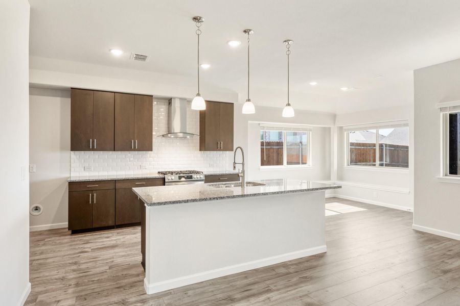 Kitchen with large island, granite countertops, dark wood cabinets, white tile backsplash, and pendant lights over open floor plan