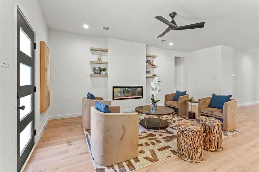 Living room featuring light wood-style flooring, a glass covered fireplace, recessed lighting, and a ceiling fan Living room featuring light wood-style flooring, a glass covered fireplace, recessed lighting, and a ceiling fan