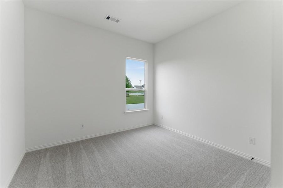 This room features light gray carpet flooring, white walls, and a single window providing natural light and a view of the outdoors
