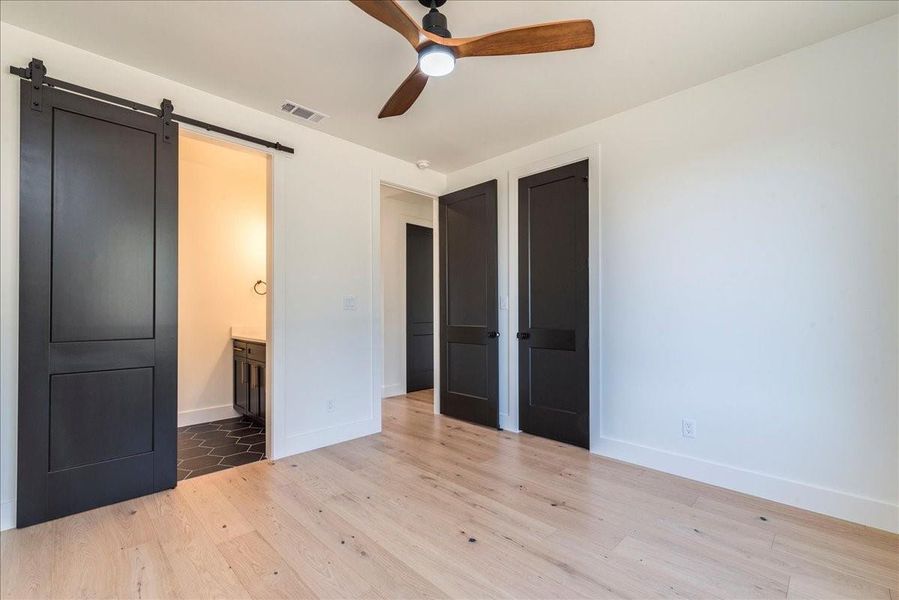 The guest bedroom shares a generous Jack-and-Jill bathroom, featuring a barn door for easy access.