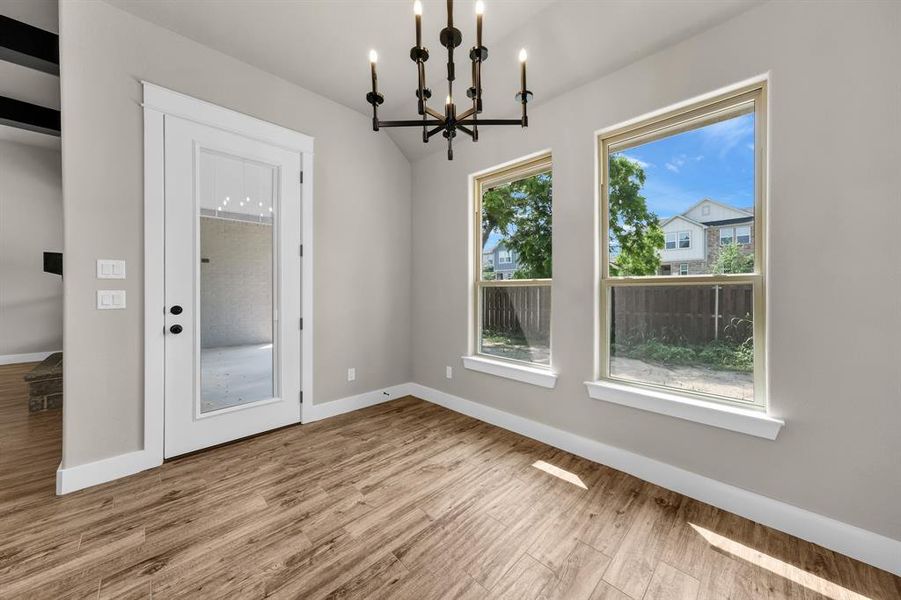 Empty room featuring a wealth of natural light, an inviting chandelier, and light hardwood / wood-style floors