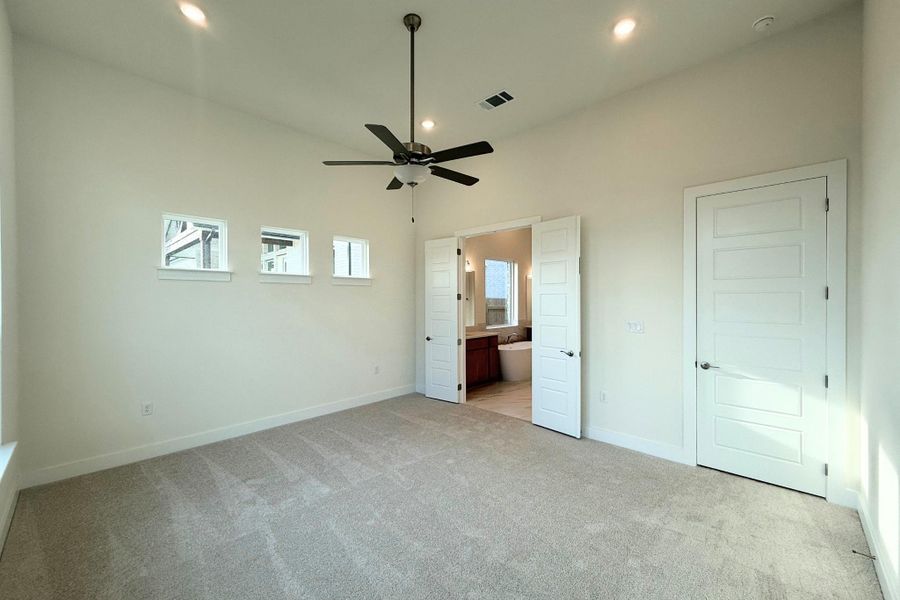 Spacious carpeted room featuring a high vaulted ceiling, recessed lighting, and a ceiling fan