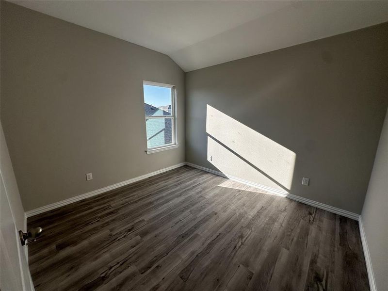 Spare room featuring dark hardwood / wood-style flooring and vaulted ceiling