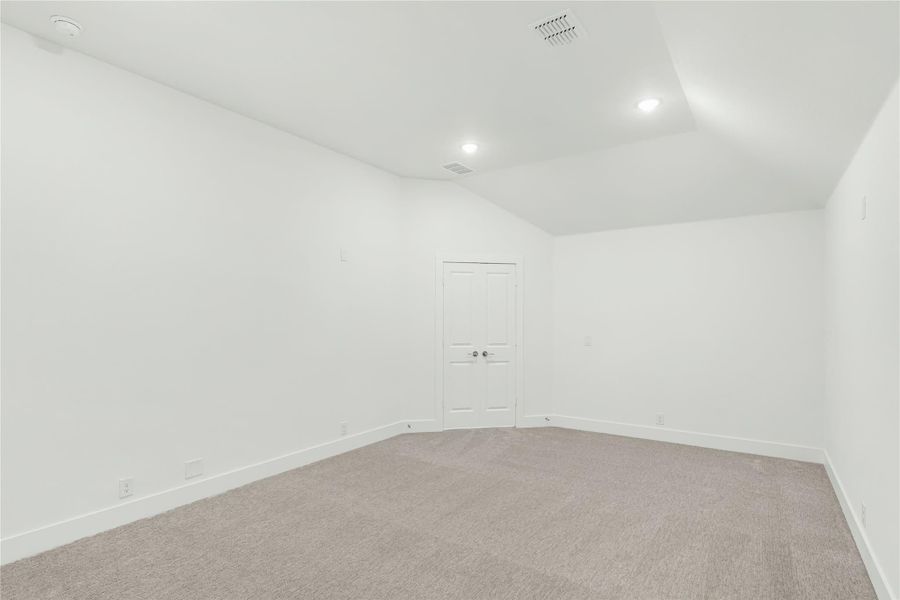 Empty room with vaulted ceiling, gray carpet, white walls, and recessed lighting