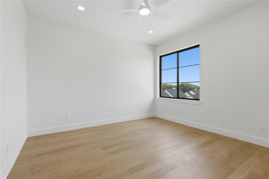 Room featuring a modern black-framed window, wood-finish flooring, recessed lighting, a ceiling fan, and crisp white walls