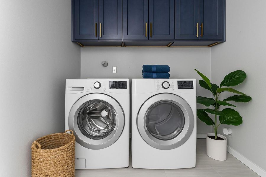 This modern laundry room is large enough for front-loading washer and dryer units, sleek navy cabinets with gold handles, and a stylish plant for a touch of greenery. The space offers lots of functionality. Virtually Staged This modern laundry room is large enough for front-loading washer and dryer units, sleek navy cabinets with gold handles, and a stylish plant for a touch of greenery. The space offers lots of functionality. Virtually Staged